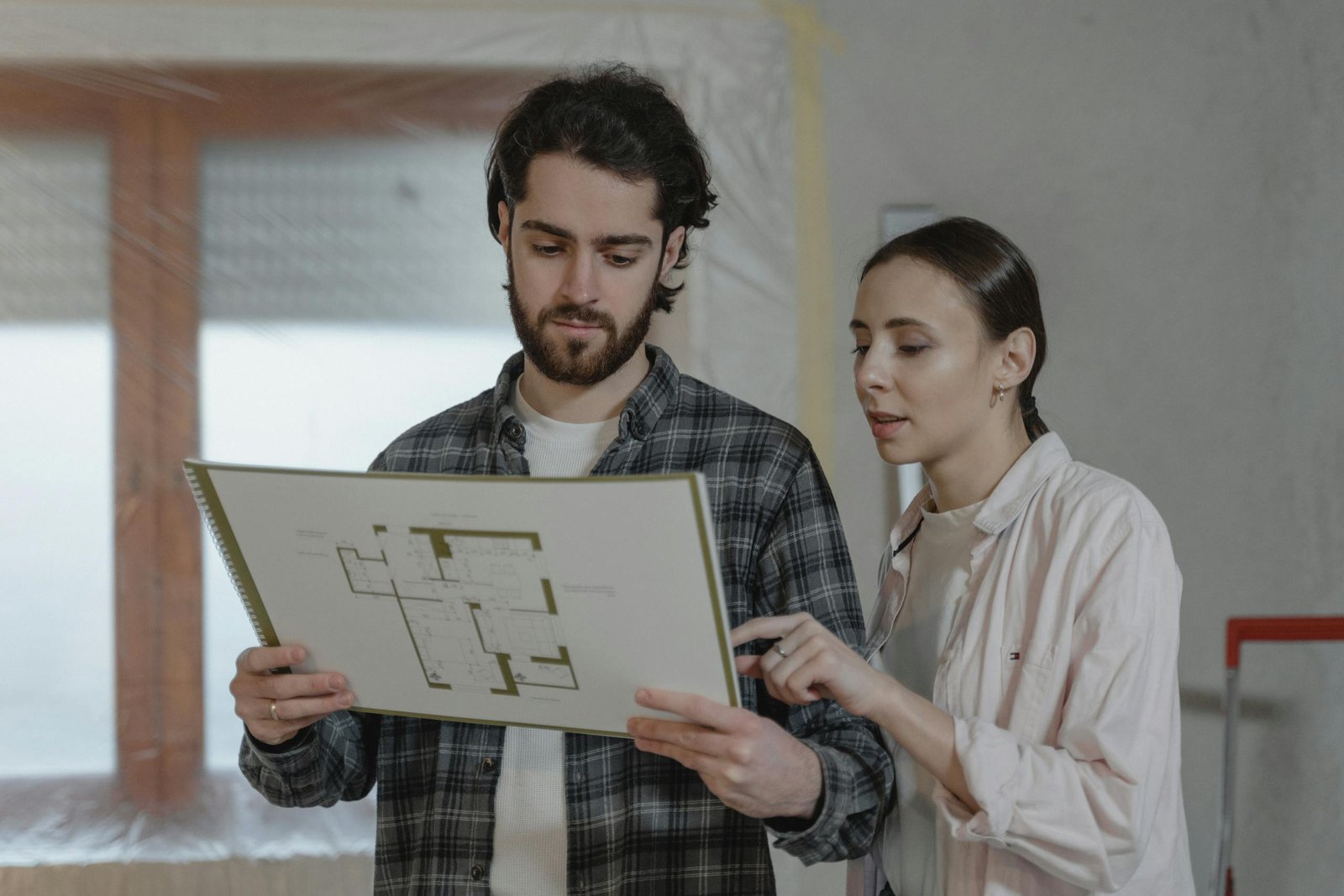 Homeowners reviewing a floor plan for a home improvement project, relevant to rekeying and lock upgrades after moving into a new Auburn WA home